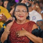 Costureira vira cantora aos 63 e sobe ao palco de longo vermelho com plumas
