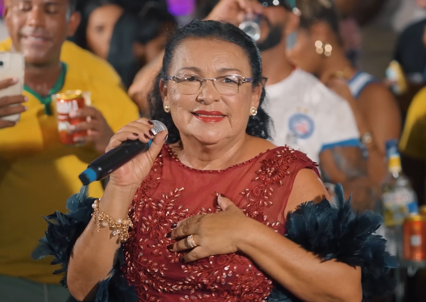 Costureira vira cantora aos 63 e sobe ao palco de longo vermelho com plumas